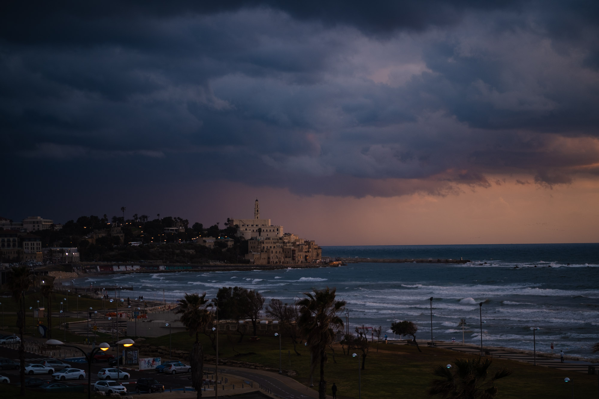 Dark storm clouds gather over the coastline and buildings of Jaffa.